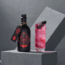 The Illusionist Gin FC Bayern Muenchen Edition Bottle Next to Red Cocktail in a Glass